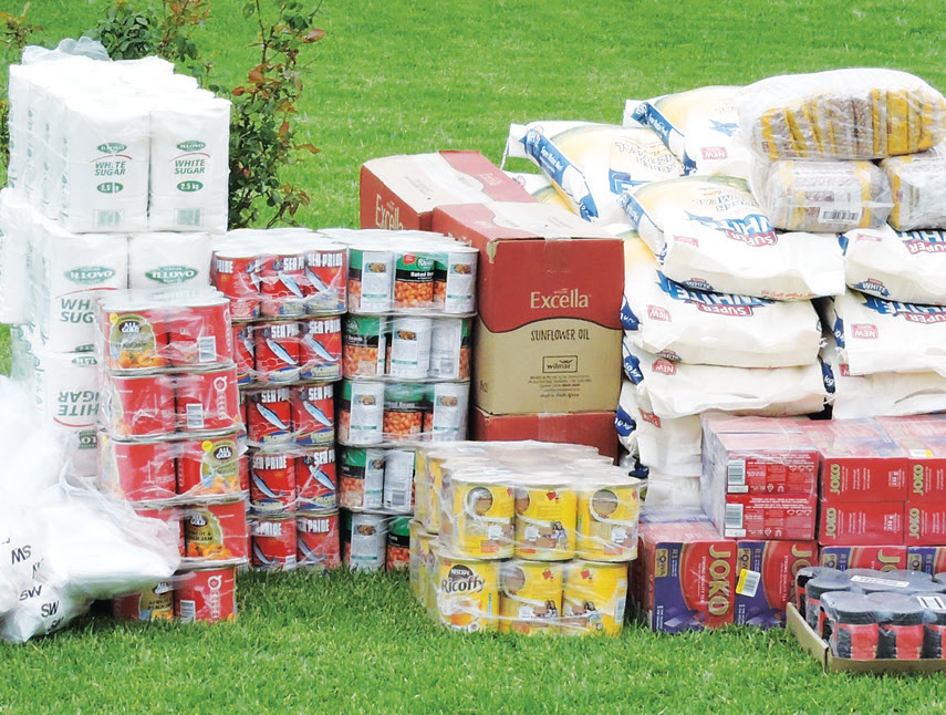 Stack of donated non-perishable tinned food items, sugar, flour and coffee