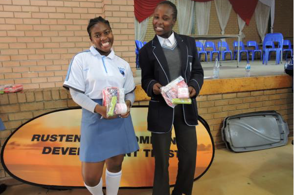Two school girls in uniform posing with dignity packs they received