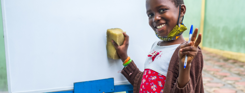 A closeup shot of a black male child erasing a whiteboard - education concept