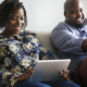 Businesswoman sitting next to her husband on the tablet using digital resources
