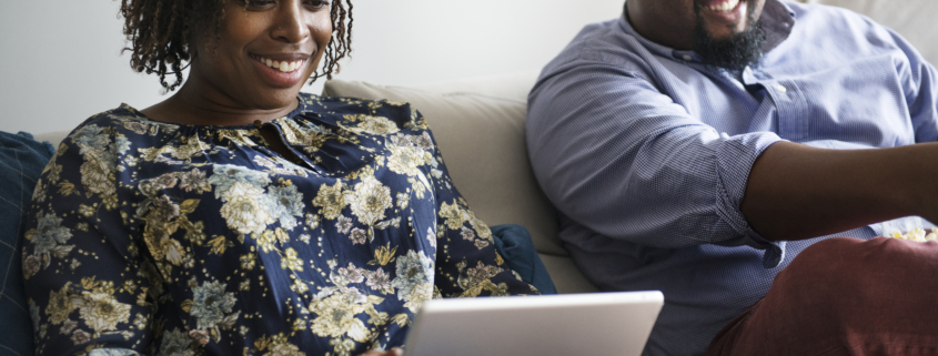 Businesswoman sitting next to her husband on the tablet using digital resources