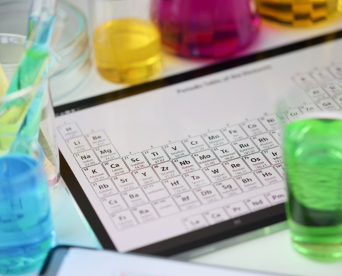 Digital tablet with periodic system of elements lying on table in laboratory closeup. Checking water quality concept