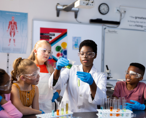 Diverse female teacher and schoolchildren doing an experiment in chemistry class. Education, inclusivity, elementary school and learning concept.
