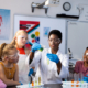 Diverse female teacher and schoolchildren doing an experiment in chemistry class. Education, inclusivity, elementary school and learning concept.