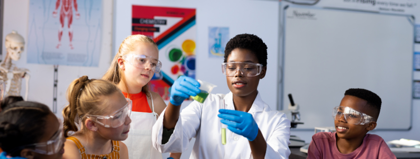 Diverse female teacher and schoolchildren doing an experiment in chemistry class. Education, inclusivity, elementary school and learning concept.