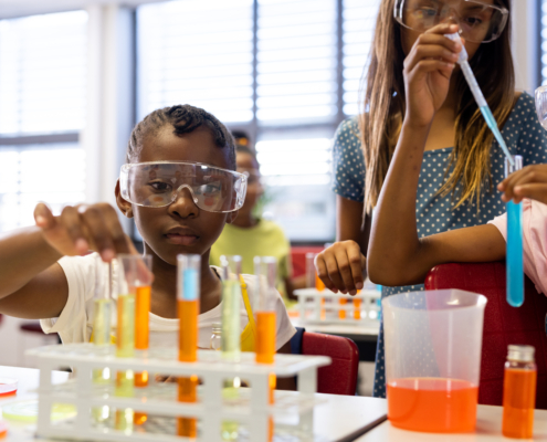 Diverse schoolgirls with chemistry items and liquids in elementary school class. School, learning, childhood, science, chemistry and education, unaltered.
