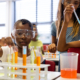 Diverse schoolgirls with chemistry items and liquids in elementary school class. School, learning, childhood, science, chemistry and education, unaltered.