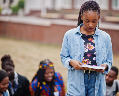 Group of five african college students spending time together on campus at university yard. Black afro friends studying. Education theme.