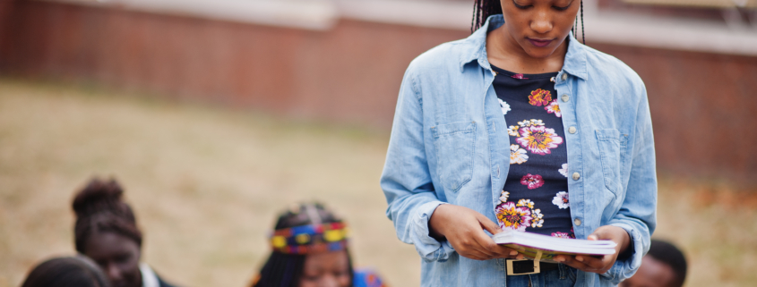 Group of five african college students spending time together on campus at university yard. Black afro friends studying. Education theme.