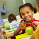 Portrait of cute girl giving crayon to classmate at lesson