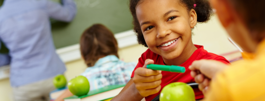 Portrait of cute girl giving crayon to classmate at lesson