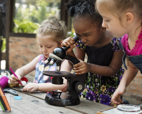 Little Girls Using Microscope Learning Science Class