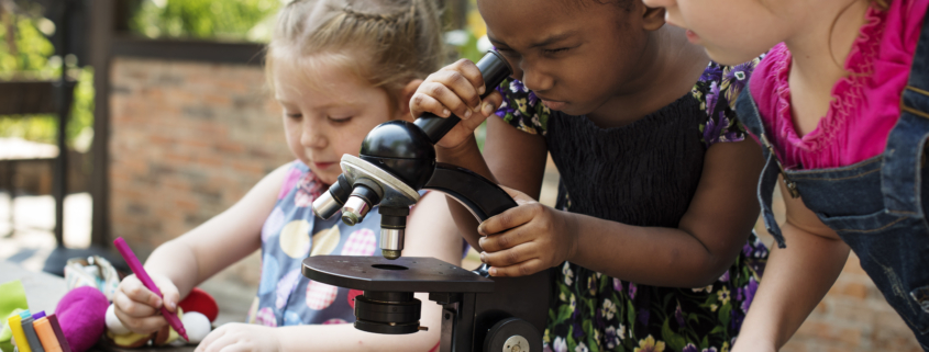 Little Girls Using Microscope Learning Science Class