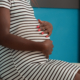 Portrait of future mother with baby bump waiting on medic to start health care consultation in cabinet. Woman expecting child sitting on bed before examination appointment with obstetrician.
