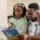 Reading storybook together, African father and child sharing smiles at home. Family, bonding, parenting, storytelling, togetherness, happiness