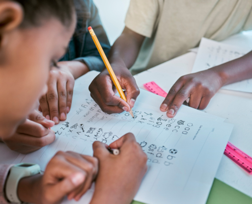 School, children and hands writing for teamwork with learning activity in classroom group together. Young kids and students working on literacy and academic exercises for development at desk
