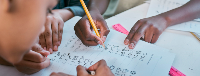 School, children and hands writing for teamwork with learning activity in classroom group together. Young kids and students working on literacy and academic exercises for development at desk