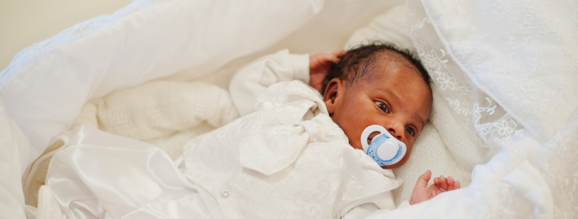 Small tiny newborn african baby laying in his crib