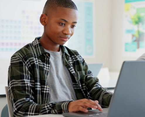 Teenager child, laptop and education at school with research, coding or computer science. Black kid in classroom with technology for learning, problem solving and system or software study at academy.