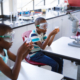Two african american boys wearing protective glasses holding a beaker in science class at laboratory. school and education concept