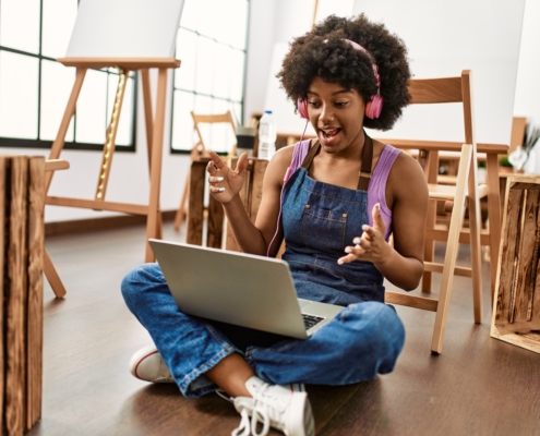 Young african woman using laptop and headphones at art studio
