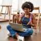Young african woman using laptop and headphones at art studio