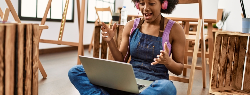 Young african woman using laptop and headphones at art studio