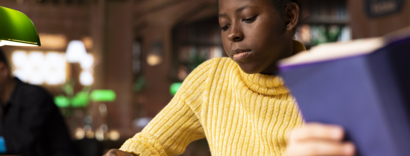 Young teenagers reading literary texts at the library as part of their curriculum, preparing for literature class lesson and enhancing their academic focus. Girls read the mandatory books titles.